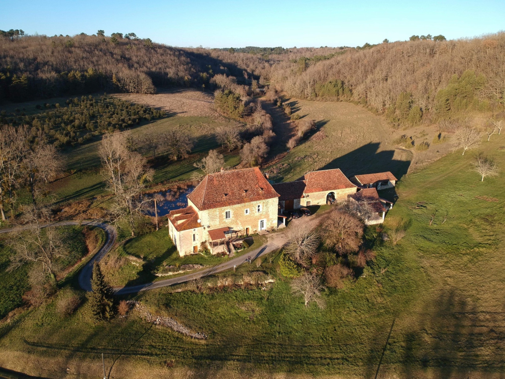 Ferme de la Massinie, vue aérienne Vue aérienne de la Massinie, à Issac : la maison et ses dépendances au fond d'un vallon boisé