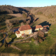 Vue aérienne de la Massinie, à Issac : la maison et ses dépendances au fond d'un vallon boisé